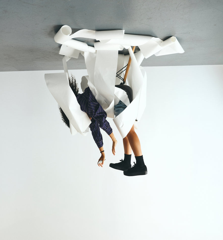 Malia upside down in an office chair, surrounded by long strips of white paper