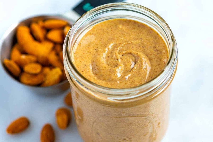A jar of almond butter with almonds